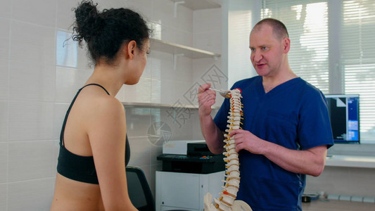 脊椎按摩疗法医生在治疗前检查年轻女子显示脊柱样本上图片