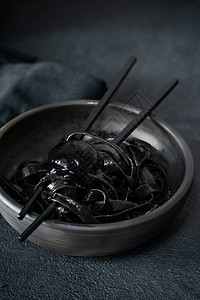 黑色面食与墨鱼水在黑色背景上的黑色盘子罕见的意大利海鲜酱黑图片
