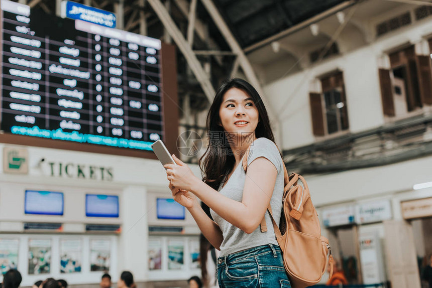 快乐的亚洲女孩旅行者在火车站售票厅图片