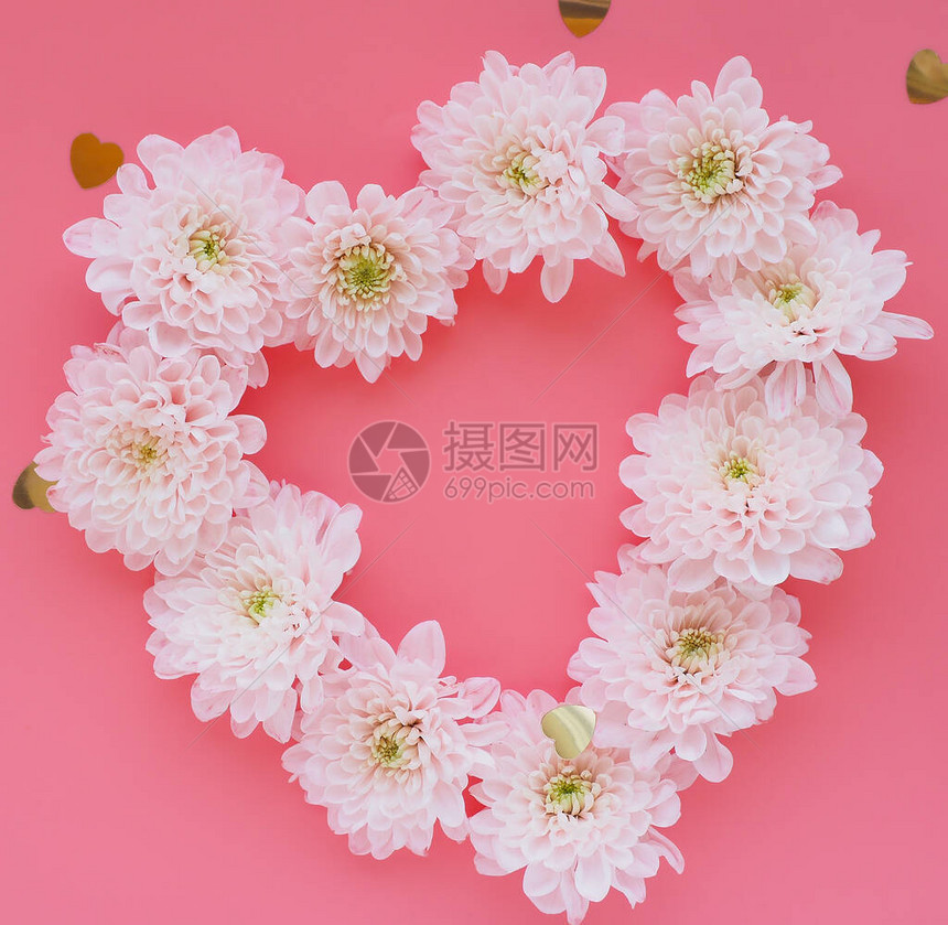 由粉红色背景和塑料心上菊花的柔软粉红色花朵所制成的贺卡心脏图片