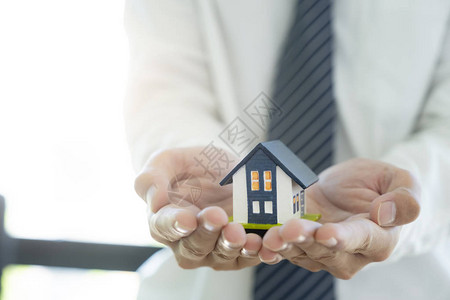 商家手握着救小房子的房屋模背景图片