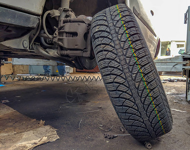 新的橡胶轮胎准备好更换目前没有轮胎的汽车上的轮胎车轮图片