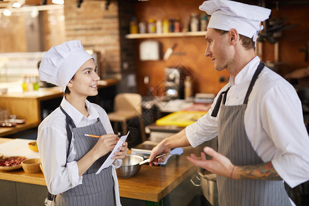专业厨师培训年轻厨师在餐厅厨房工作时笔记的侧图片