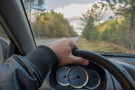 汽车的仪表板和方向盘的视图透过挡风玻璃可以看到道路和秋天的森林车速表转速表燃油表和冷却液温度指示器蓝色背景背景图片