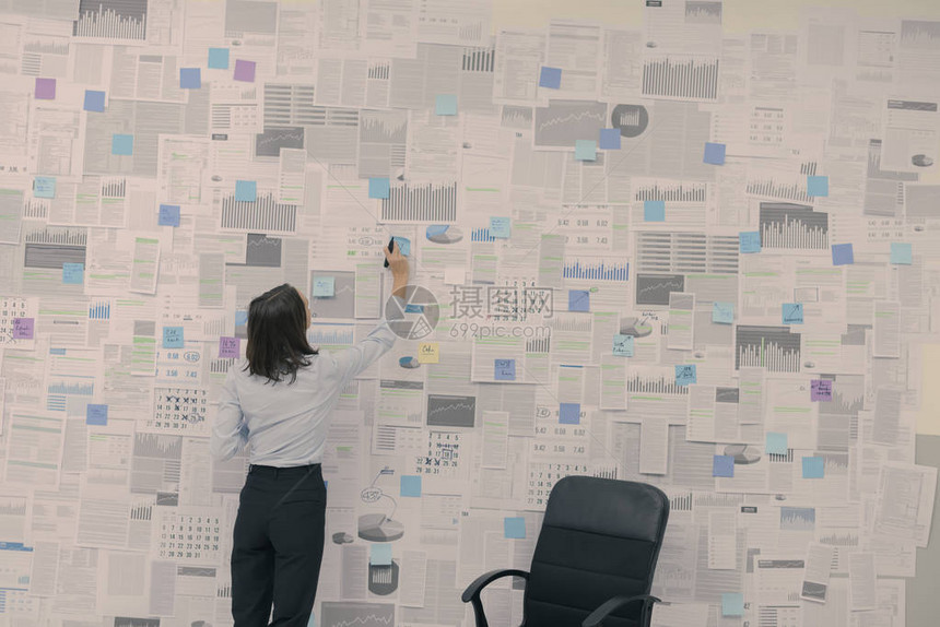 企业女商人检查挂在墙上的财务数据和报告管图片
