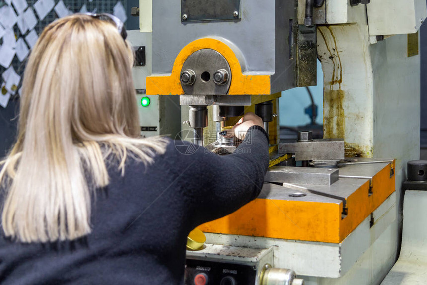 一位长头发的金发女郎在金属加工厂使用机械冲压机工作选择图片