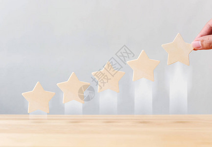手拿着木制五星形状生长增加桌子上的质量最佳优秀商业服务评级图片