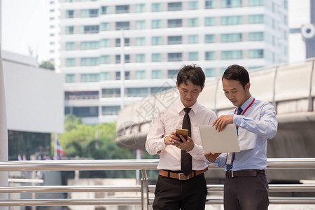 两位商人正在用智能手机和笔记本做商业概念图片