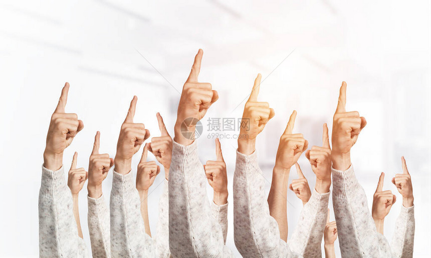 一排人的手用食指显示手指向的手势一群人的手在光模糊的背景上打手势许多手臂一起举图片