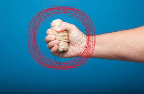 蓝色背景上握着一卷绳子或绳子的右手拳头图片