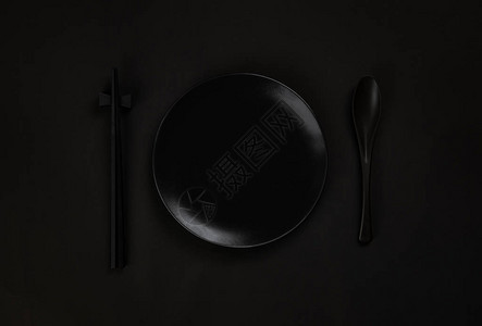 在黑色背景上用勺子和筷子设置黑色盘子图片