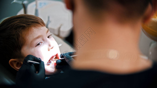牙医在现代牙医诊所检查一个男孩图片