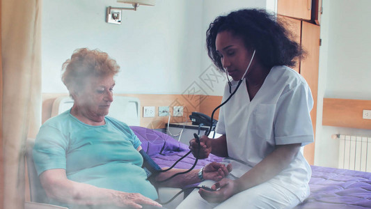 非洲女医生在病床上探望老年女患者康复图片