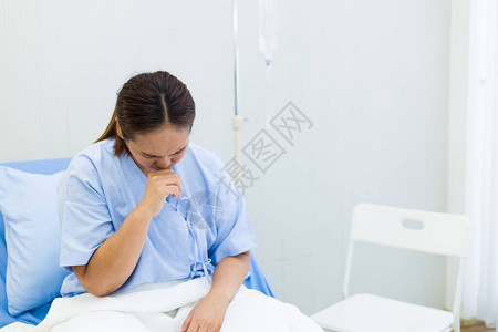 亚裔女病人在医院床上时有严重咳嗽症状高清图片