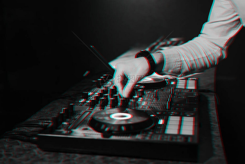 DJ在一个夜总会的展位上用他的手在音乐控制器板上混合电子音乐具有3D故障虚拟现图片
