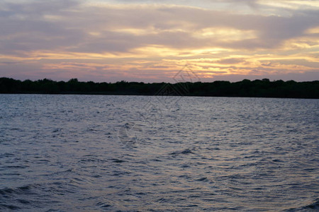 波光粼的湖面远处的山脉和落日的天空图片