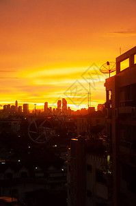 日落时的城市风景卫星天线和天线电视在住宅大楼前台屋顶上图片