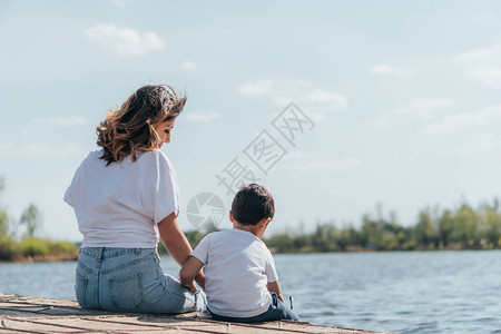 美丽的母亲坐在河边看着儿图片
