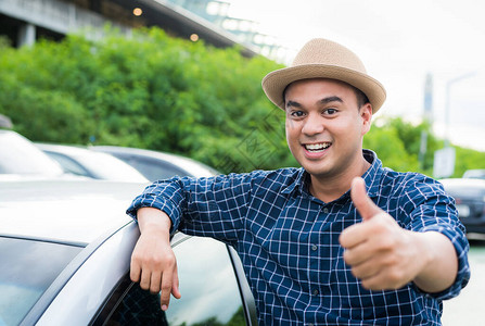 年轻的亚洲男人用汽车竖起大拇指图片