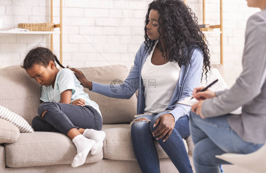 非裔美国人母亲在心理咨询时安慰她心烦意乱的不听话的小女儿图片