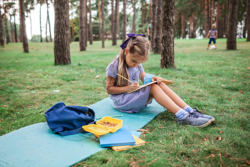 回到学校的新常态在大流行现实中的露天课上坐在绿草地上的小学者女孩安全混合教育社交距离规则图片