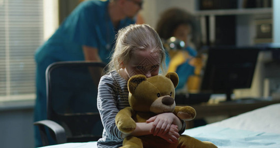 医院里悲伤的女孩怀里抱着一只玩具熊悲图片