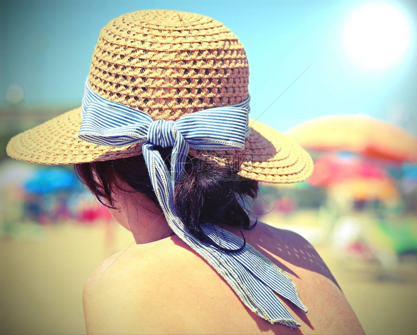 在阳光明媚的沙滩上戴草帽的感女人图片
