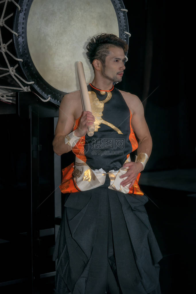 Taiko鼓手站在大鼓前站在舞台上的黑图片