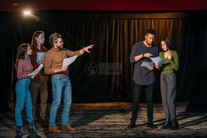 多民族青年演员和女演员在舞台上与成熟的戏剧导演一图片