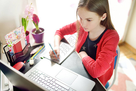 青春期前的女学生在家里用笔记本电脑做作业孩子使用小工具学习孩子们的在线教育和远程学习隔离期间在家上背景图片