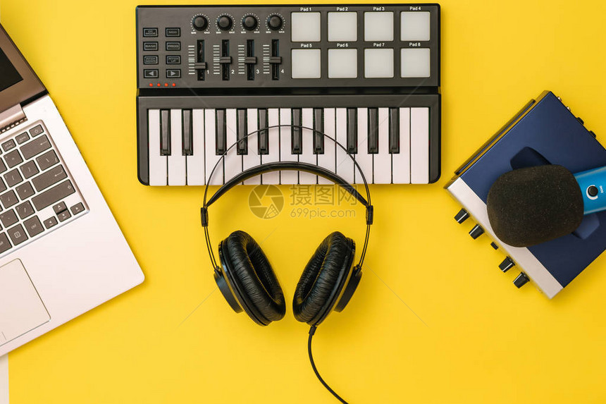 黄色背景上的音乐混音器笔记本电脑和声卡上的耳机工作场所组织的概念用于录音交流和图片