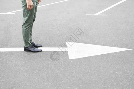年轻人站在路上有箭头标记选择的概念图片