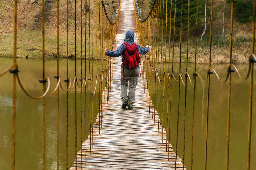 旅行者沿着春季河的吊桥行走图片