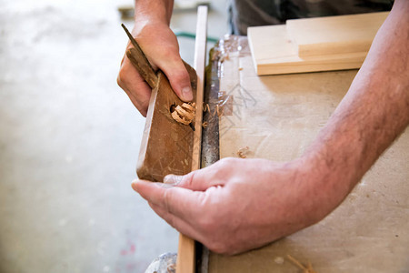 木匠在木工车间的木板上用刨刀图片