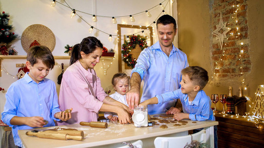 全家人在圣诞节前夕一起为圣诞节做姜饼五口之家正在用圣诞装饰在厨房图片
