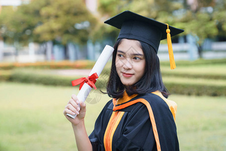 年轻的亚洲女子大学毕业生在毕业典礼上获得大学位证书后图片