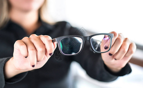 拿着新眼镜的女人镜片和眼镜由专业配镜师修理和修理诊所的验光师眼科医生或眼科医生双焦点或多焦点规格验光图片