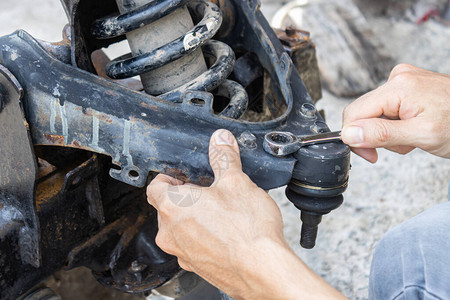 汽车修理工或汽车修理工的手在汽车或汽车修理店拧紧图片