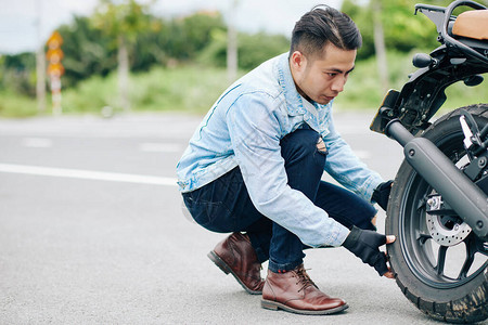 英俊的越南摩托车驾驶员脱下摩托车的轮胎图片