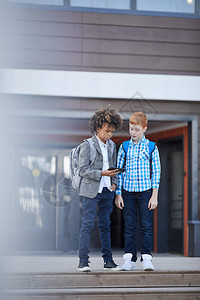两个男生站在学校门口一起玩手机图片