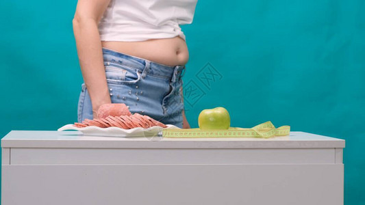 担心胖肚子的女人应该在青苹果和香肠之间做出选择背景图片