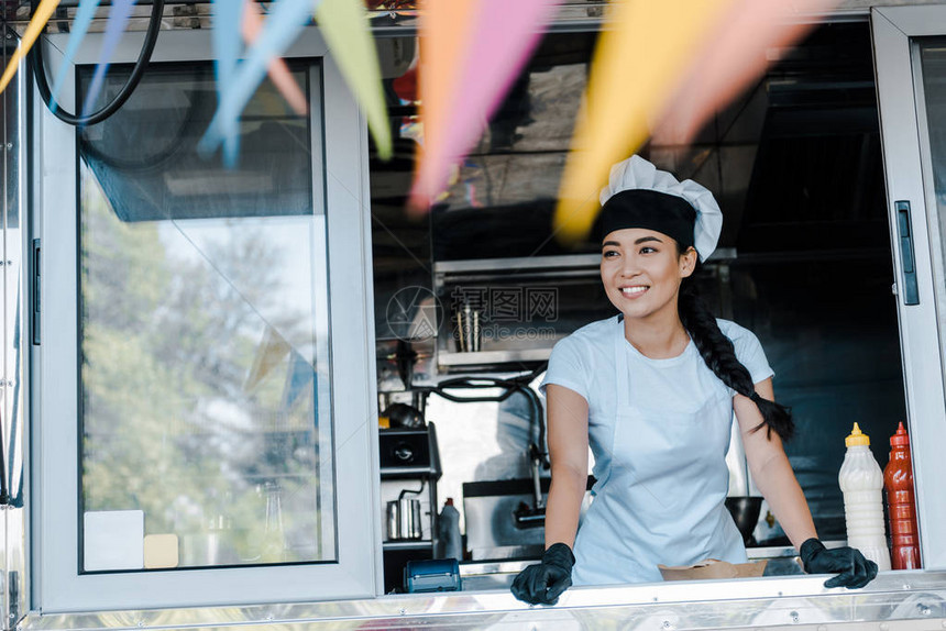 穿着帽子和厨师制服的快乐的亚洲女在食图片