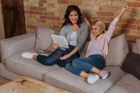 坐在母亲身边的快乐和兴奋的孩子在沙发上图片