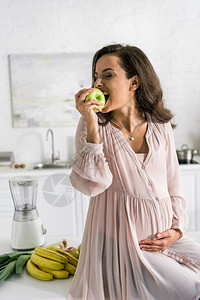 快乐的孕妇在香蕉附近吃苹果图片
