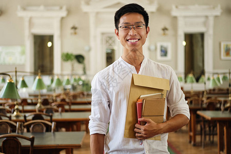 年轻笑的年青男学生在眼镜里用笔记本愉快地看着大学图片