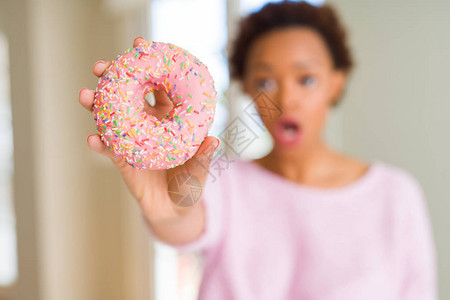 年轻非洲女吃粉红糖甜圈图片
