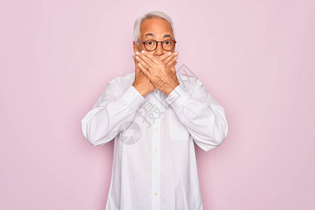 中年高龄的灰发男子戴眼镜和穿粉红色背景的商业衬衫图片