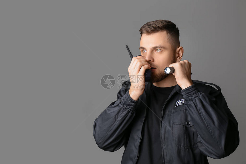 灰色背景中带手电筒的男保安图片