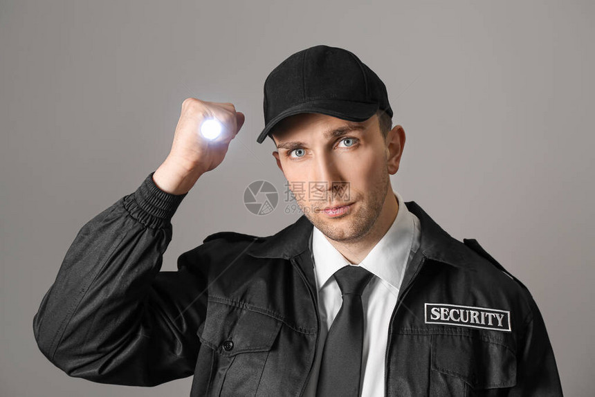 灰色背景中带手电筒的男保安图片