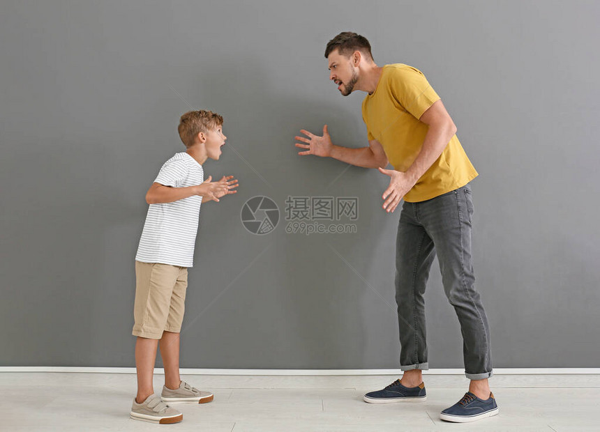 在灰墙附近吵架的父亲和他的小儿子图片